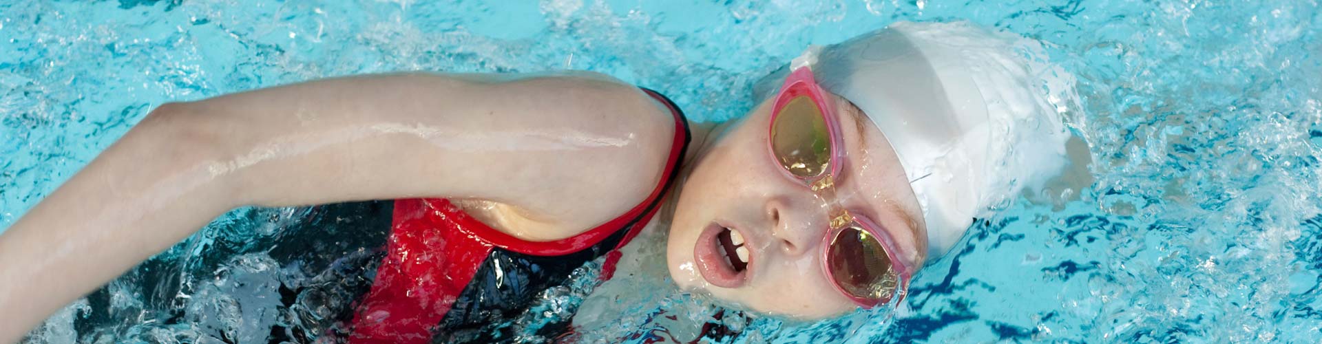 Girl with goggles and cap swimming