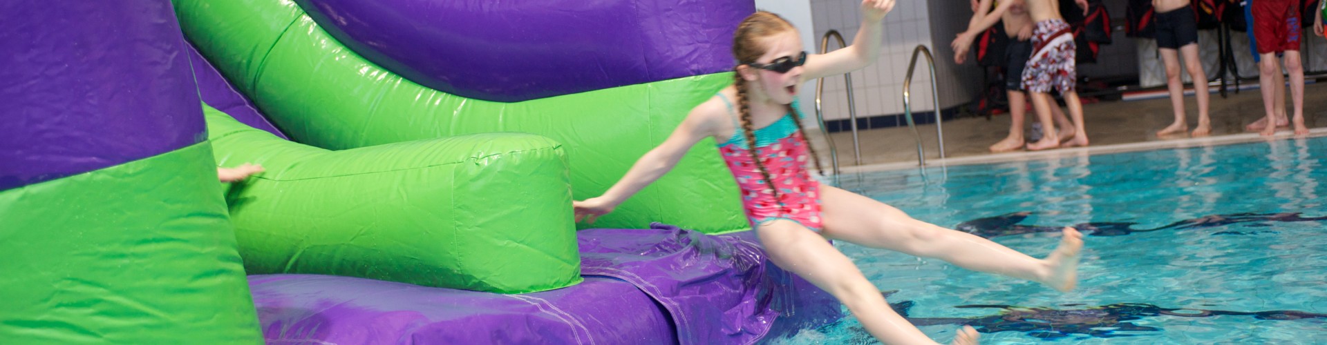 Girl on inflatable pool slide laughing